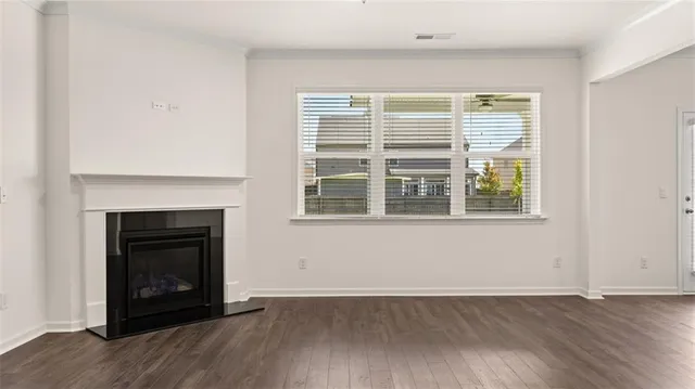 a view of an empty room with window and wooden floor