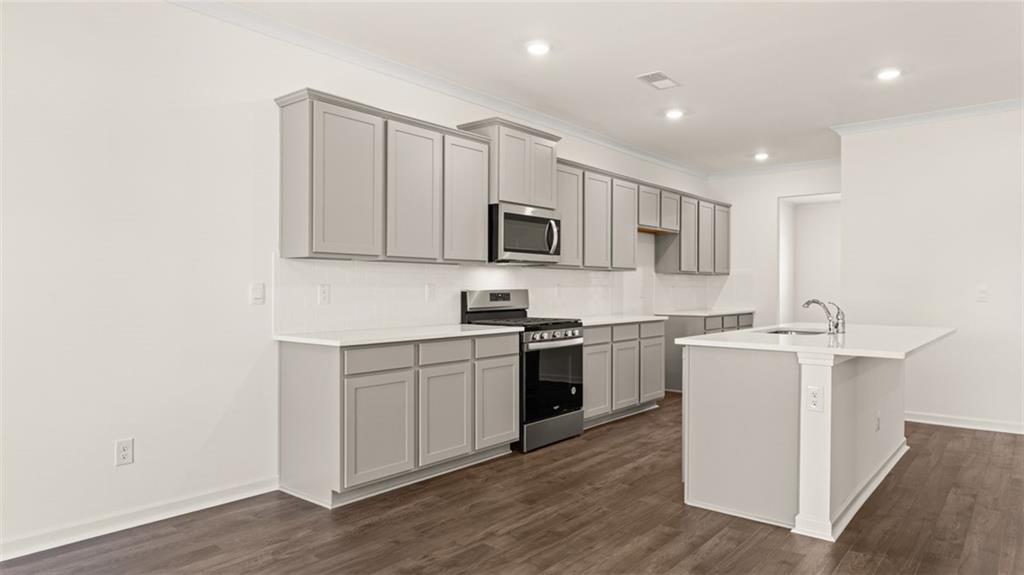 71 Weymouth Drive Locust Grove, GA 30248 - Photo 7 of 56 a kitchen with stainless steel appliances granite countertop a stove top oven a sink a refrigerator and white cabinets with wooden floor