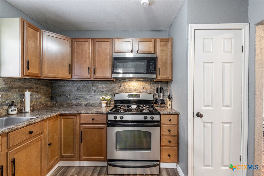 1609 South 39th Street Temple, TX 76504 - Photo 7 of 19 a kitchen with granite countertop a stove top oven microwave and cabinets