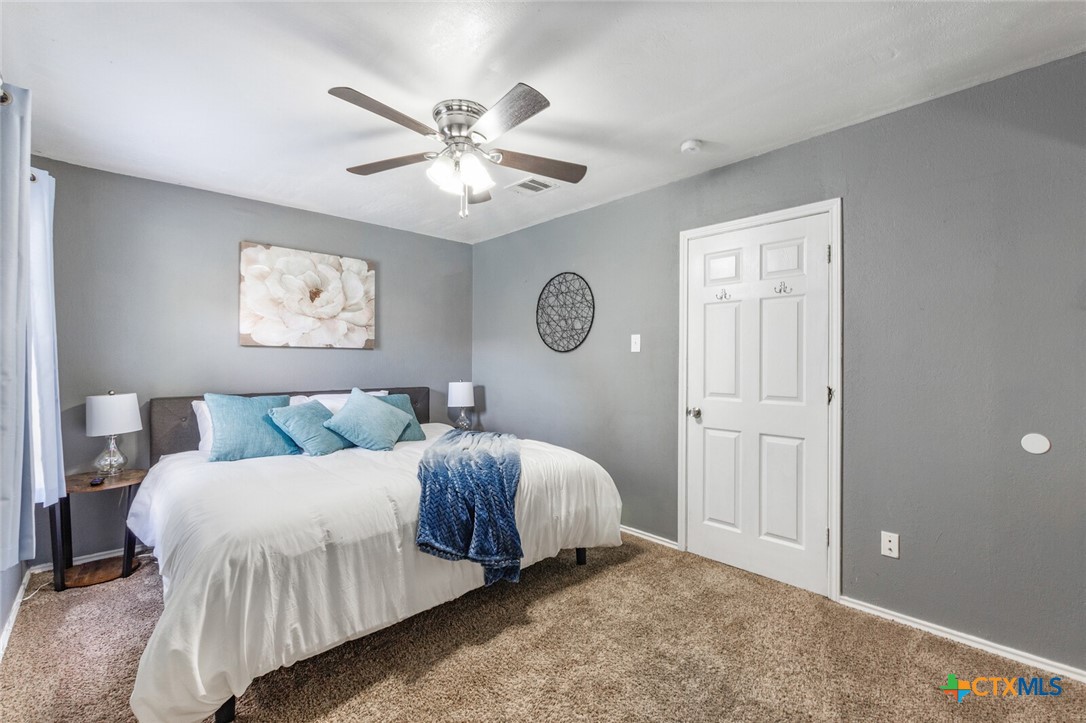 1609 South 39th Street Temple, TX 76504 - Photo 10 of 19 a bedroom with a large bed and a chandelier