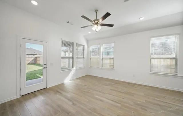 a view of an empty room with a window and wooden floor