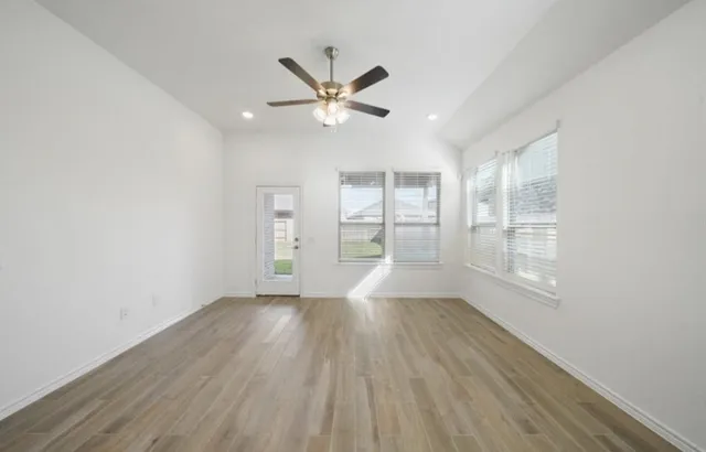 a view of empty room with wooden floor and fan