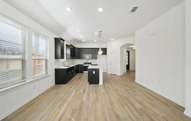 a large kitchen with stainless steel appliances kitchen island a large counter top and a wooden floors