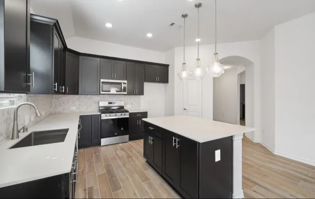 a large kitchen with a sink a counter top space a stove and cabinets