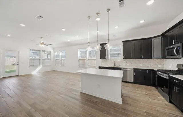 a large kitchen with granite countertop a stove top oven a sink a counter space and cabinets