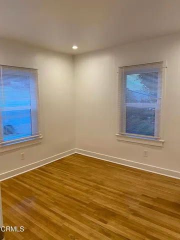 a view of an empty room with wooden floor and windows