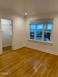 a view of an empty room with wooden floor and a window
