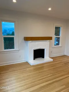 a view of an empty room with wooden floor and a fireplace