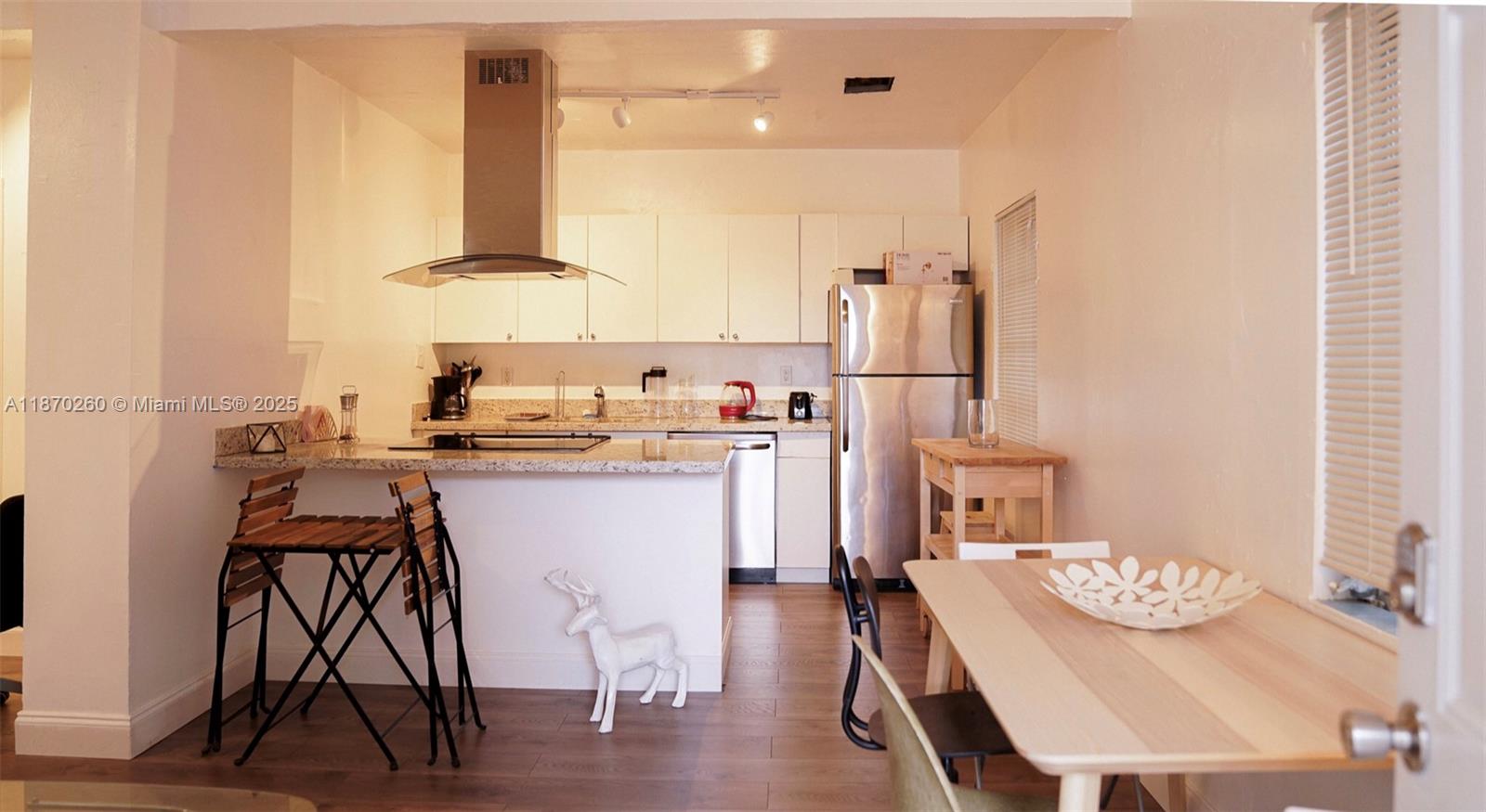 68 Northwest 45th Street, Unit 2 Miami, FL 33127 - Photo 14 of 20 a kitchen with a table chairs refrigerator and cabinets