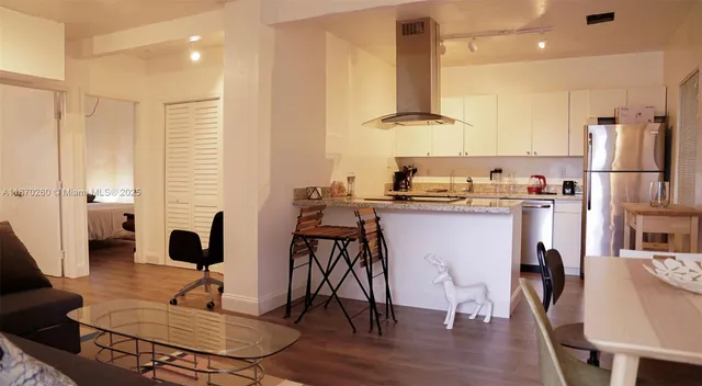 a living room with furniture kitchen view and large wooden floor