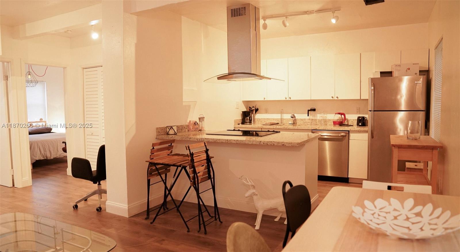 68 Northwest 45th Street, Unit 2 Miami, FL 33127 - Photo 9 of 20 a kitchen with stainless steel appliances kitchen island granite countertop a table chairs and a refrigerator