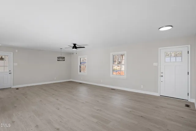 an empty room with windows and ceiling fan