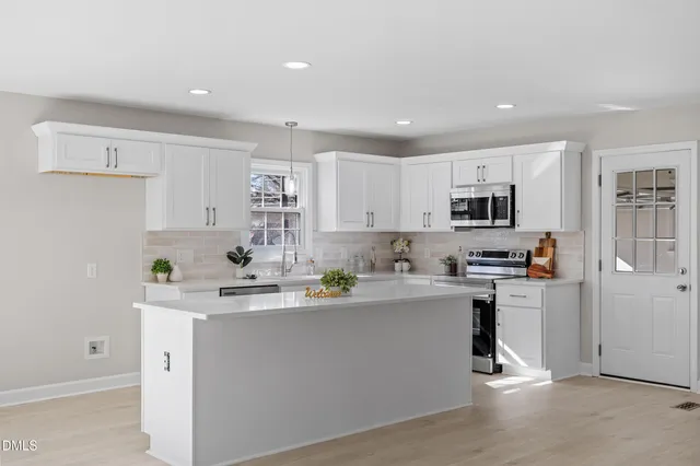 a kitchen with stainless steel appliances granite countertop a sink dishwasher a refrigerator and white cabinets with wooden floor