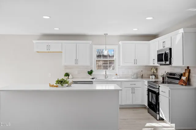 a kitchen with stainless steel appliances a sink a stove a microwave a sink a refrigerator and cabinets