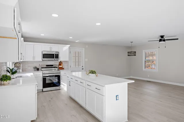 a kitchen with a sink white cabinets and white appliances