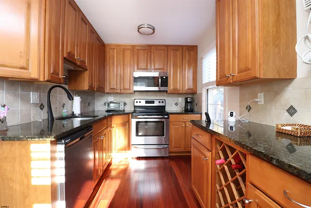 a kitchen with granite countertop a sink a counter space appliances and cabinets