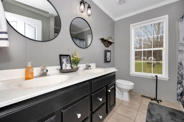 a bathroom with a sink a mirror a toilet and a window
