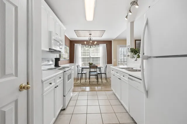 a large kitchen with white cabinets and white appliances