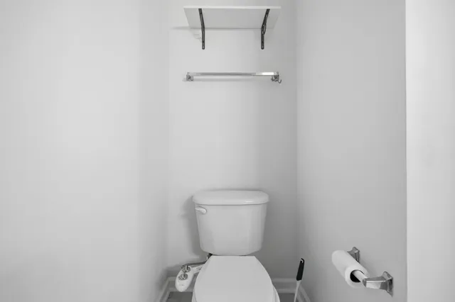 a white toilet sitting next to a white wall