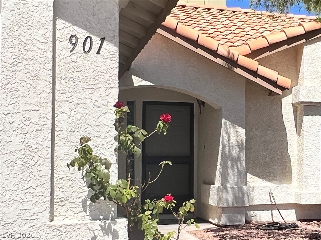 901 Dodge Street Henderson, NV 89002 - Photo 1 of 1 A terracotta-tiled roof crowns this inviting entry, adorned with vibrant roses.