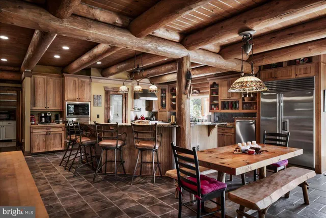 a living room with a dining table a chandelier a sink and a dining table with the kitchen view