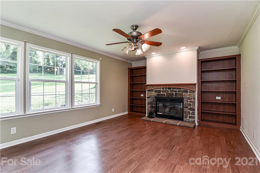 699 Pleasant Hill Road Clyde, NC 28721 - Photo 16 of 32 wooden floor fireplace and windows in an empty room