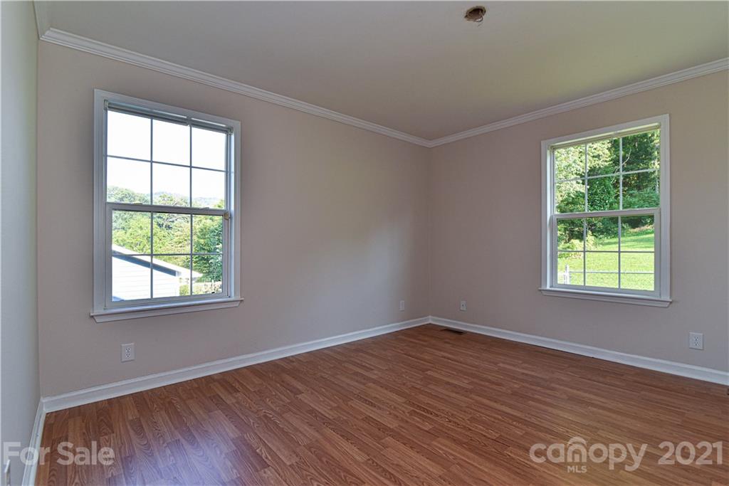 699 Pleasant Hill Road Clyde, NC 28721 - Photo 25 of 32 an empty room with wooden floor and windows