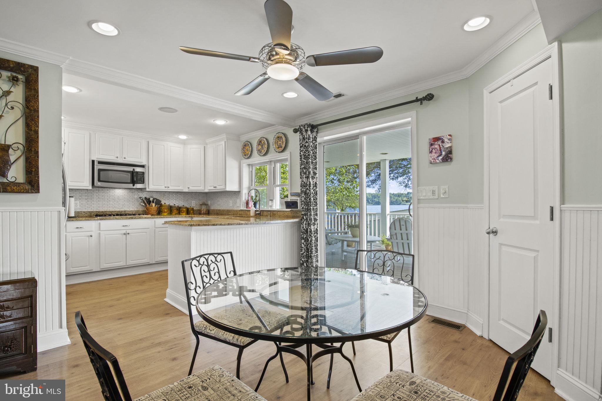 8646 Sandy Plains Road Dundalk, MD 21222 - Photo 6 of 38 a kitchen with stainless steel appliances granite countertop a stove a refrigerator a microwave oven with a dining table and chairs with wooden floor