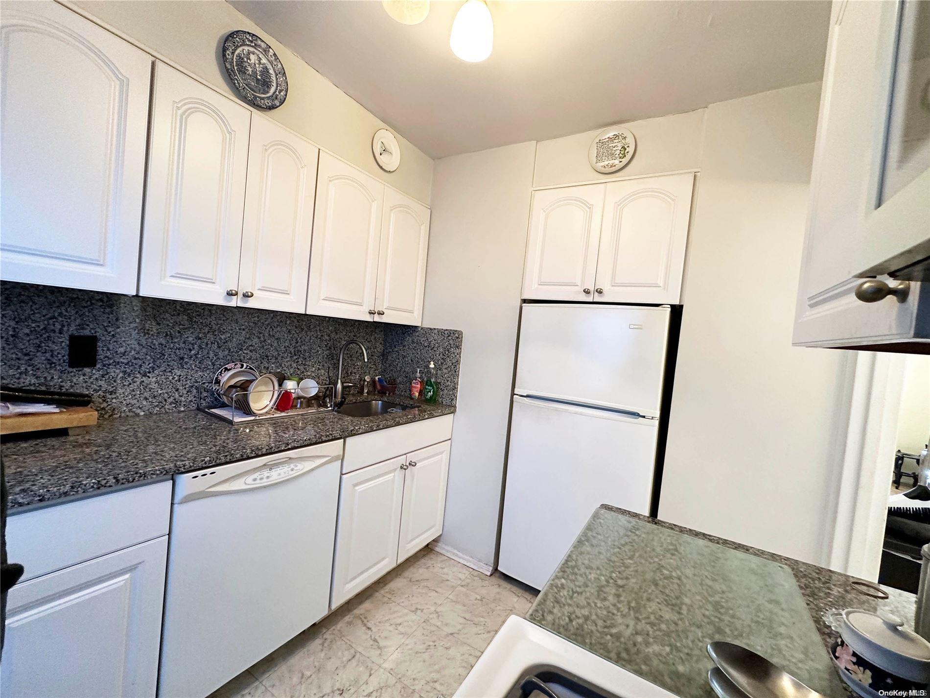 141-30 77th Road, Unit 3A Queens, NY 11367 - Photo 7 of 19 a kitchen with stainless steel appliances granite countertop a refrigerator sink and white cabinets