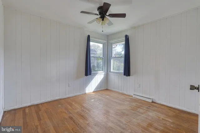 a view of empty room with wooden floor and fan