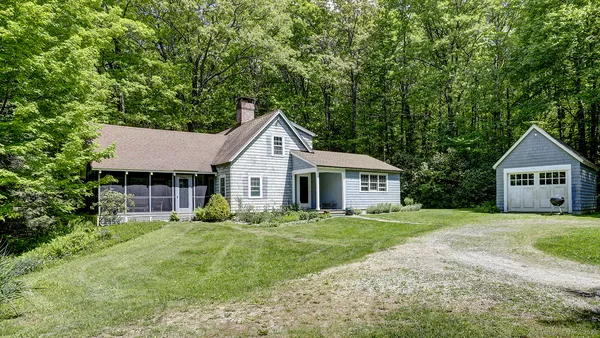 a view of a house with yard and large trees