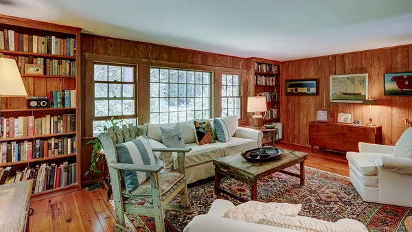 a living room with furniture a bookshelf and a window
