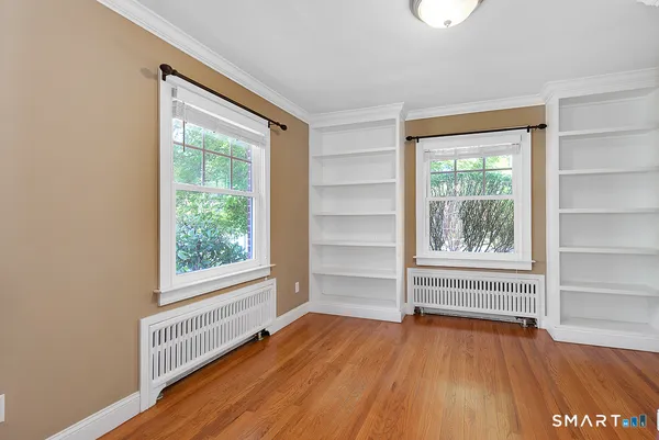 an empty room with wooden floor and windows