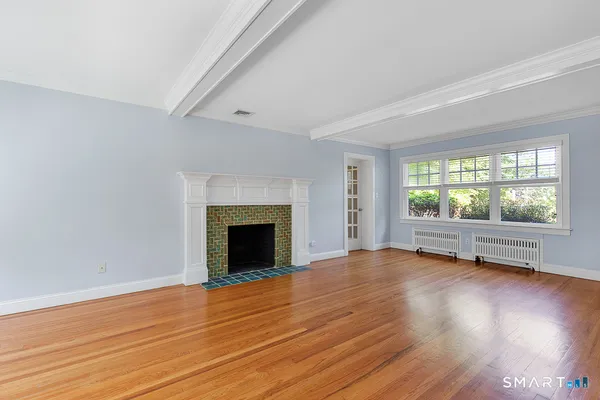 an empty room with wooden floor fireplace and windows
