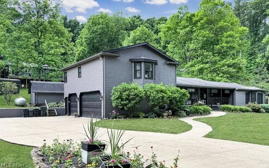 86532 North Bay Road Scio, OH 43988 - Photo 1 of 48 Exterior featuring gray horizontal siding, a two-car garage, a curved concrete pathway, a covered porch, and mature landscaping