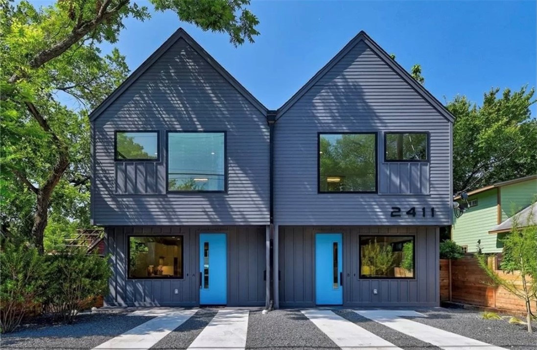 a brick house with a small yard plants and large tree