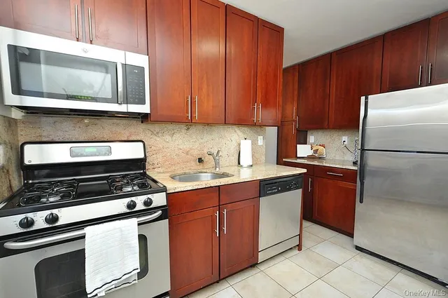 a kitchen with granite countertop wooden cabinets and stainless steel appliances