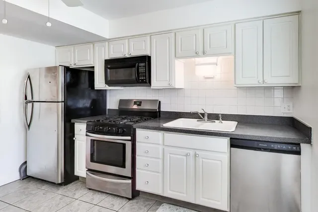 a kitchen with white cabinets sink and stainless steel appliances