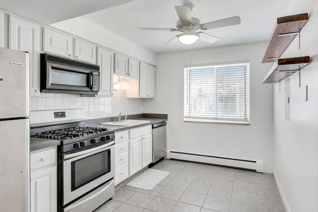 a kitchen with stainless steel appliances white cabinets granite counter tops and a window