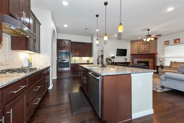 a large kitchen with stainless steel appliances kitchen island granite countertop a stove and a view of living room