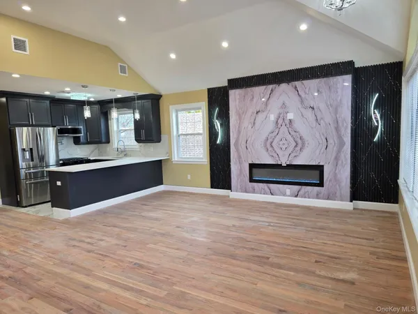 a view of kitchen with stainless steel appliances kitchen island wooden floor and living room view