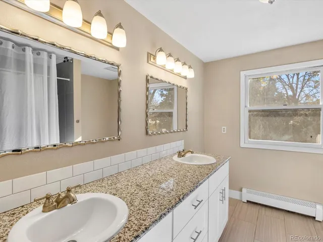 a bathroom with a granite countertop double vanity sink and a mirror