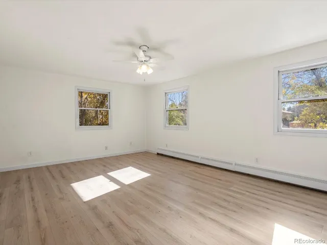 a view of empty room with wooden floor and fan