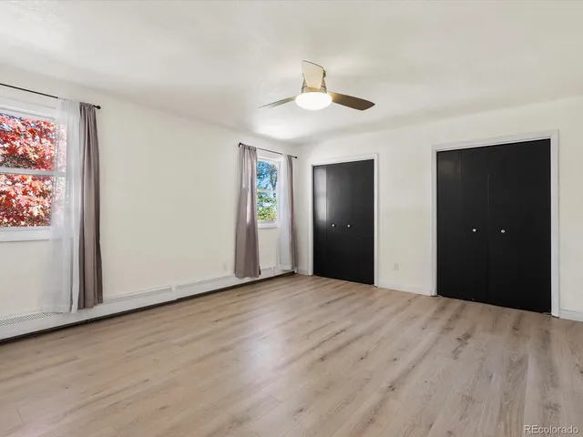 a view of an empty room with window and wooden floor
