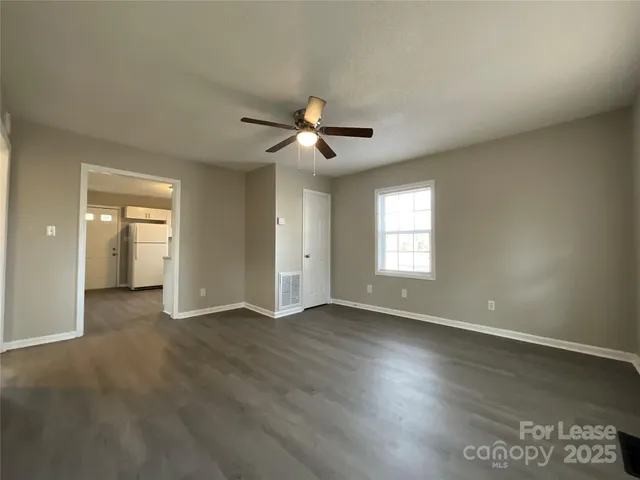 an empty room with wooden floor and a ceiling fan