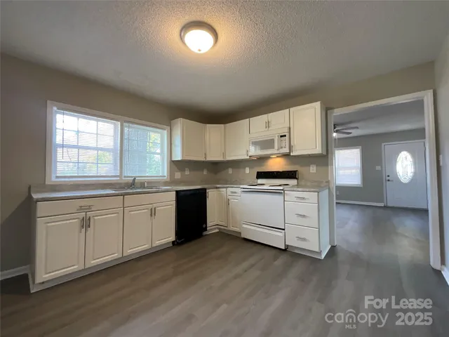 a kitchen with granite countertop white cabinets and white appliances