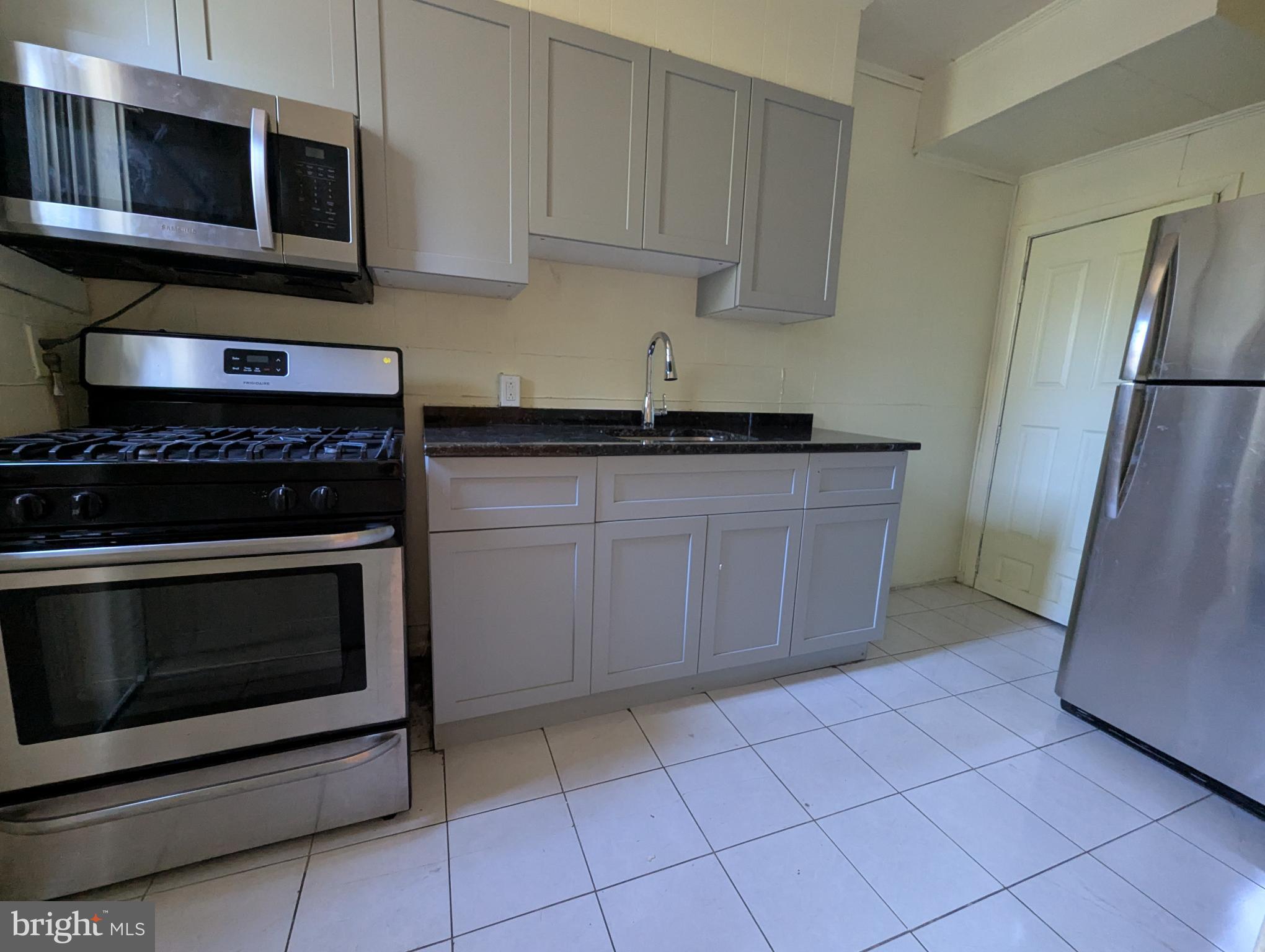 2650 South 68th Street Philadelphia, PA 19142 - Photo 5 of 12 a kitchen with stainless steel appliances granite countertop a stove microwave and cabinets