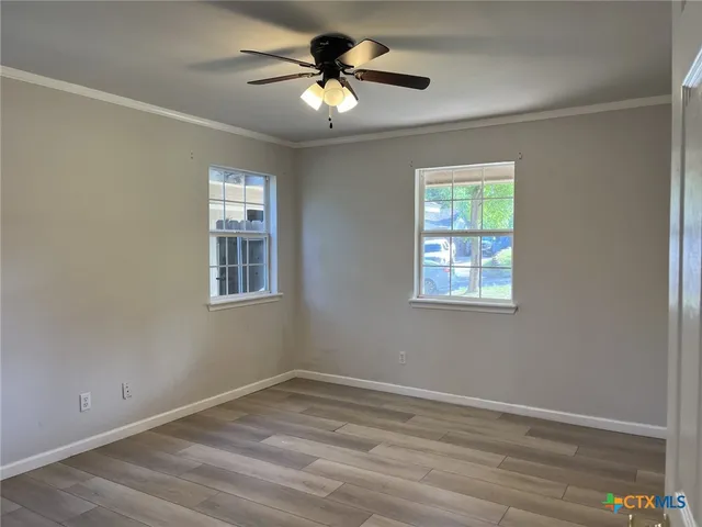 a view of empty room with window and ceiling fan