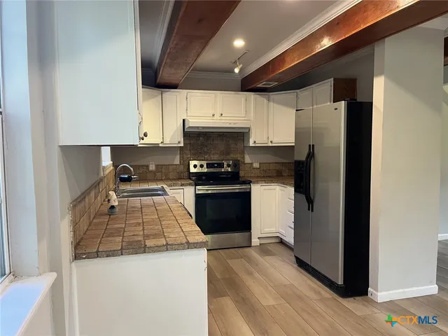 a kitchen with granite countertop a refrigerator and a stove top oven