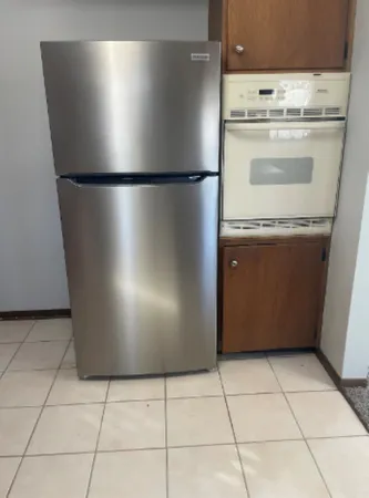 a view of a refrigerator in kitchen and empty racks